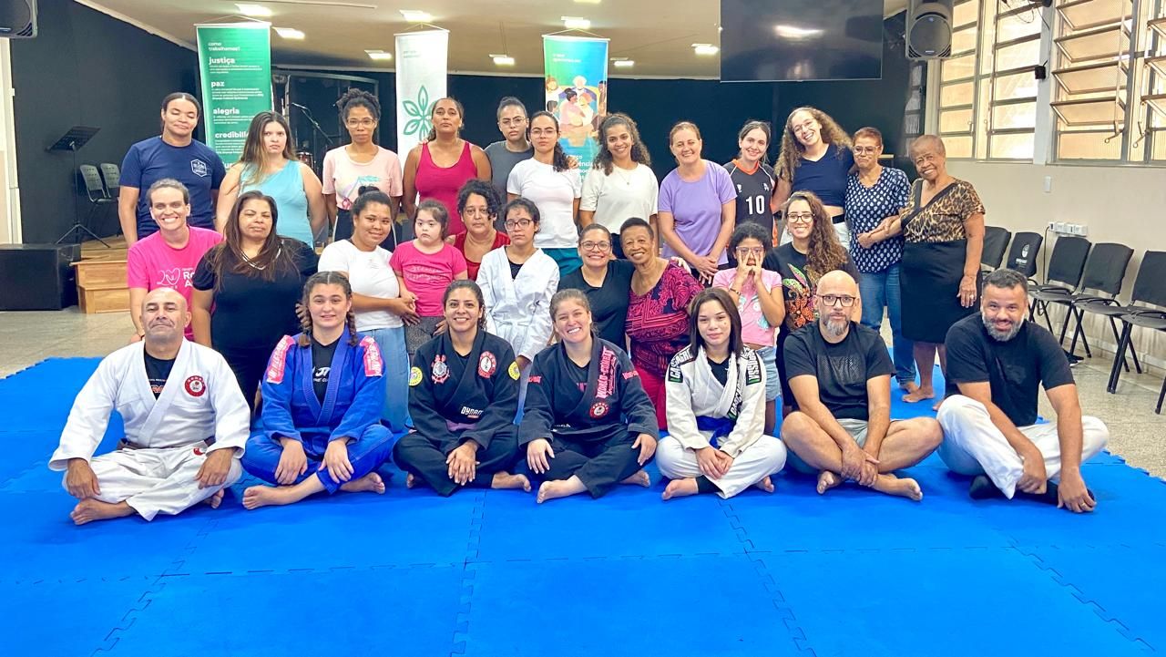 Grande grupo de participantes e equipe reunidos no tatame