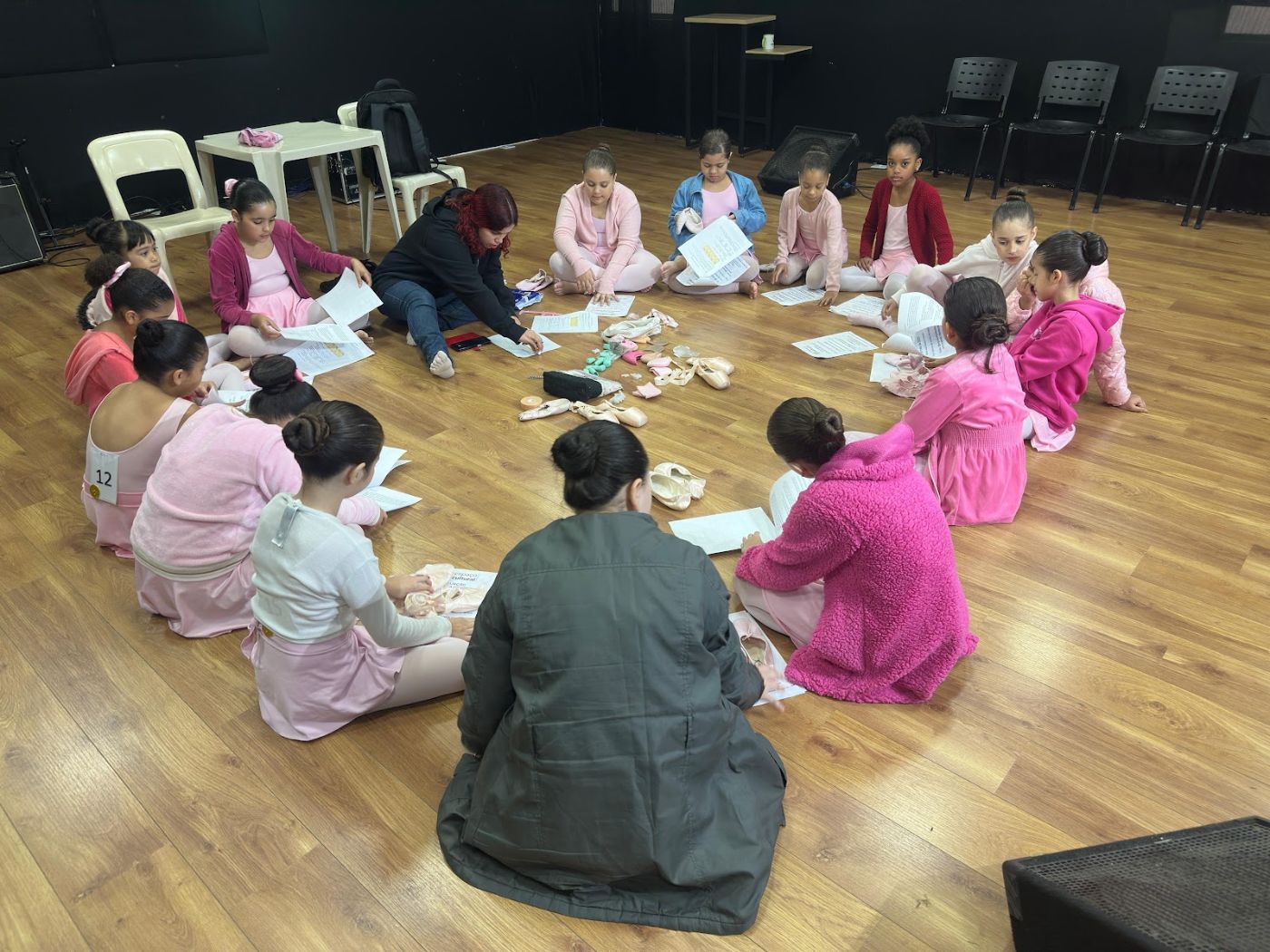 Crianças e educadores sentados em roda no auditório